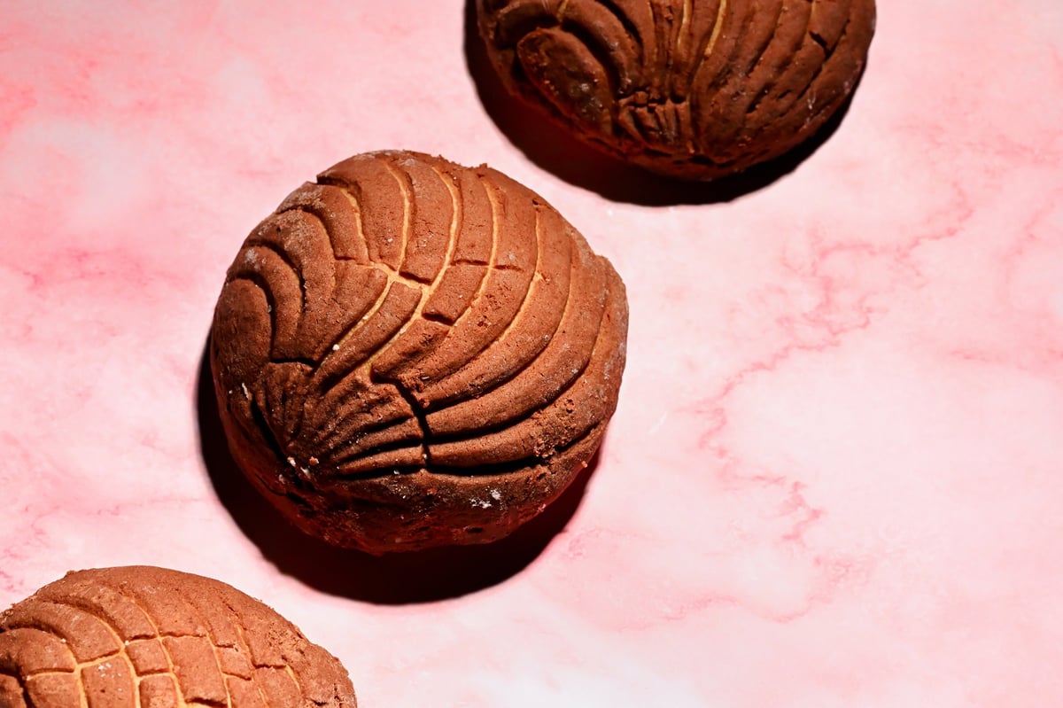 Concha de chocolate sobre fondo rosa, estilo de color blocking