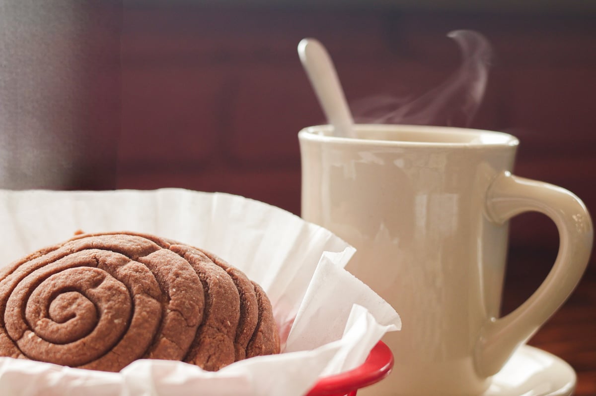 Pan dulce acompañado de una taza de café en una mesa de madera