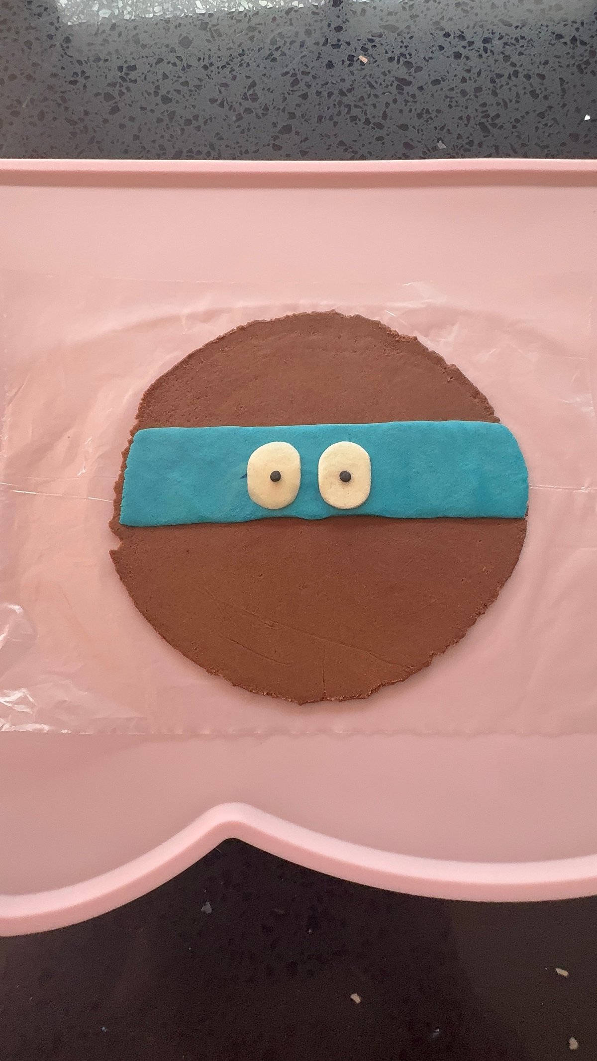 Torta decorada de chocolate con antifaz azul estilo tortuga ninja sobre plato rosa