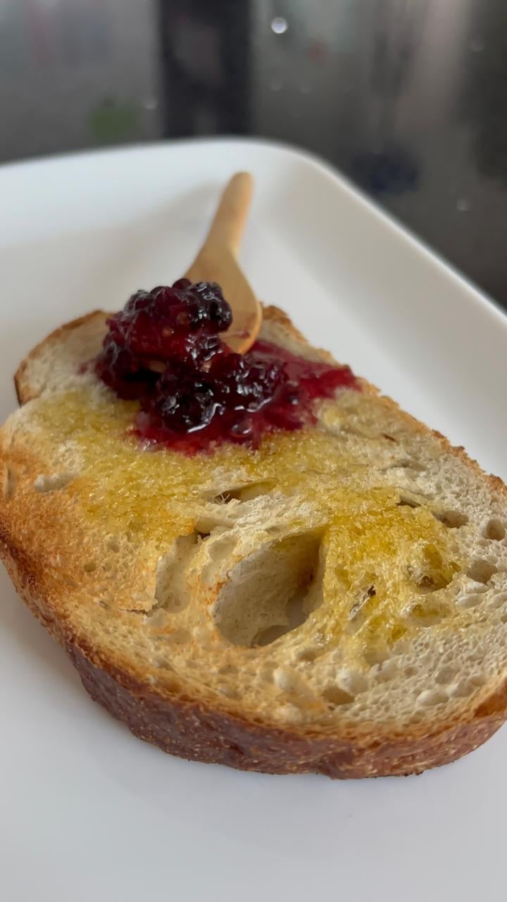 Rebanada de pan de caja artesanal con mantequilla y mermelada sobre plato blanco