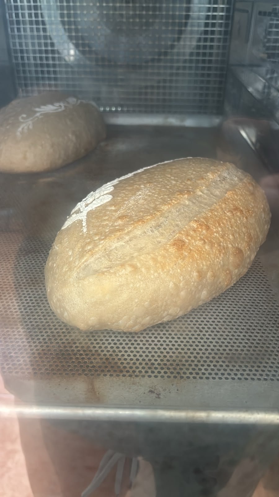 Dos hogazas de pan recién horneadas con corteza dorada dentro de un horno